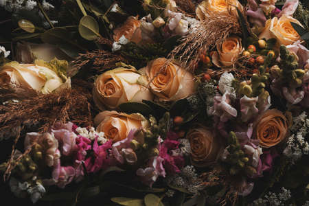 A closeup shot of a luxurious bouquet of orange and brown roses on a black background