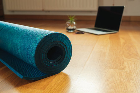 A closeup shot of a yoga mat and laptop prepared for an online yoga class at homeの写真素材