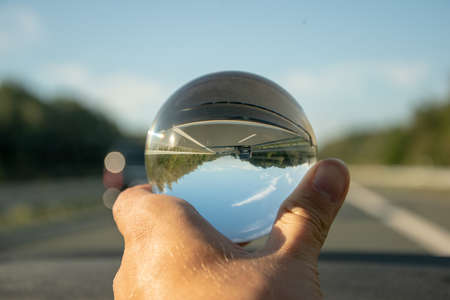 A crystal ball reflecting of a road surrounded by treesの写真素材