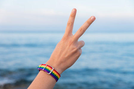 The hand of a person in a colorful bracelet gesturing the V sign