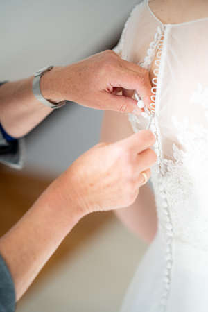 A close up shot of a person helping zip the beautiful wedding dressの写真素材