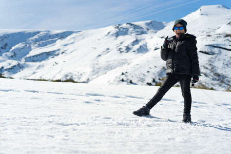 A happy Caucasian boy wearing warm clothes on the snowy mountain in the winterの写真素材