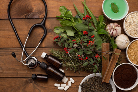 A top view of a phonendoscope next to herbs, spices, pills on a wooden surfaceの写真素材
