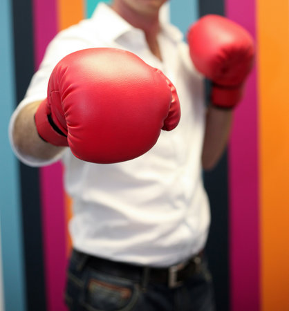 A shallow focus of a man wearing red boxing gloves with colorful backgroundの写真素材
