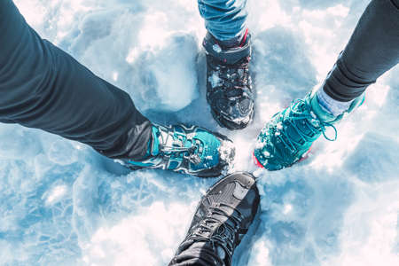 A traveler family feet in sporty winter shoes standing on a snowy groundの写真素材