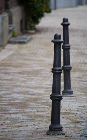 A closeup of black cast iron bollards installed in the middle of the streetの写真素材