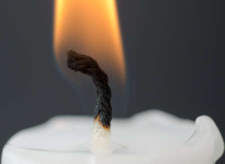 A closeup of a lit candle with burning wick