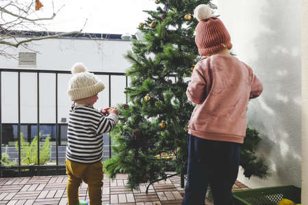 The two little kids in knitted hats decorating the Christmas treeの写真素材