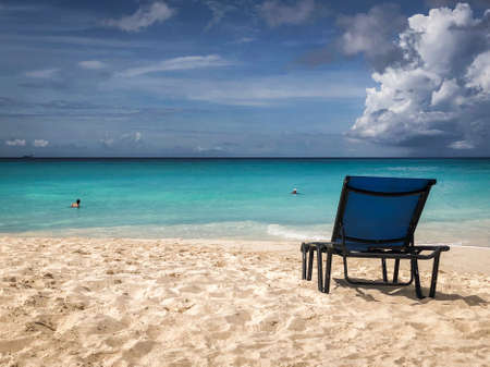 A lounge chair on the beach under cloudy skyの写真素材