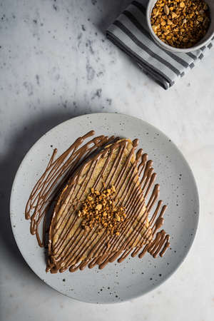 A top view shot of a piece of pancake drizzled with chocolate syrup on a white plateの写真素材