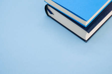 A closeup  of the hardcover books on the blue surface - space for textの写真素材