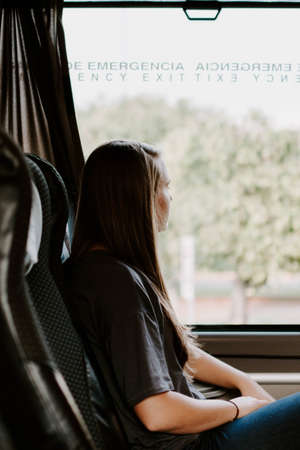 A vertical shot of a lady in a bus looking out of the window