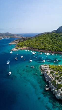 A vertical shot of a green peninsula with yachts and boats near it in Greeceの写真素材