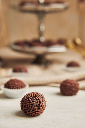 A selective focus shot of a Brazilian Brigadeiro on the background of served choco balls on a beige tableclothの写真素材