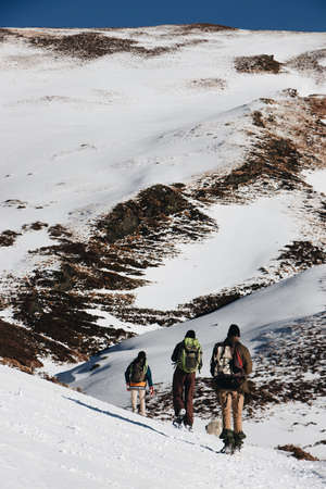 A vertical high angle shot of hikers with backpacks in the snowy mountainsの写真素材