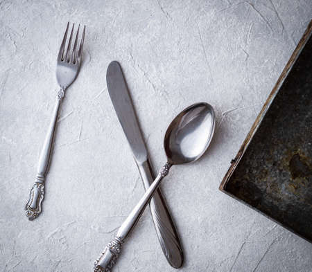A high angle shot of a fork, knife, and a spoon on a tableの写真素材