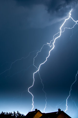 A vertical shot of lightning in the night sky over the village housの写真素材