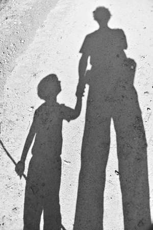 A vertical high angle shot of the shadow of a person holding the hand of a childの写真素材