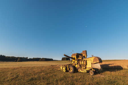 A beautiful shot of harvester machinery on the farm with a blue sky backgroundの写真素材