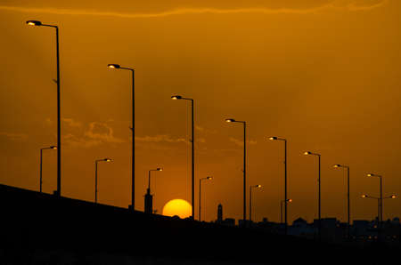 The silhouetted street lights along the road against the golden sunset sky, Riyadh, Saudi Arabiaの写真素材