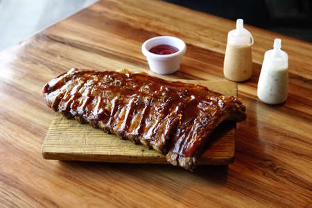 A closeup shot of pork ribs made with honey sauce on a chopping boardの写真素材