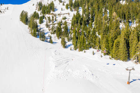 A breathtaking view of forested mountains covered in snow at daytimeの写真素材