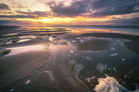 A beautiful landscape during the sunset with the reflection of clouds in low tide water in Waddenzee, Texel, The Netherlandsの写真素材