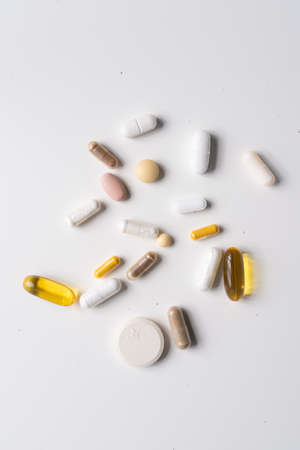 A vertical shot of different pills and capsules on a white surface