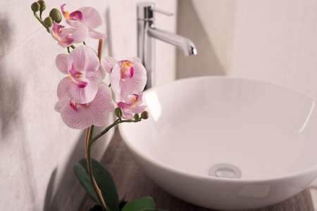 A soft focus of orchids flower beside a sink in a bathroomの写真素材