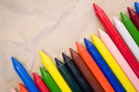A set of lined up colored wax crayons on recycled paper backgroundの写真素材
