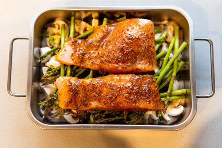 A top view of raw salmon seasoned with mustard and honey on mushrooms and green asparagus