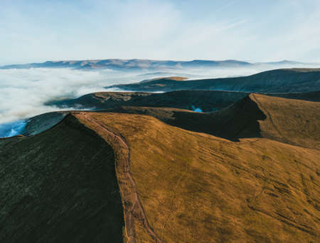An aerial shot of mountains surrounded with white cloudsの写真素材