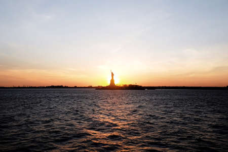The beautiful Statue of Liberty on the water captured at sunset in New York City, USAの写真素材