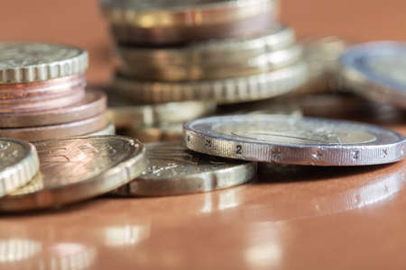 A closeup shot of a pile of colorful euro coins on wooden table surfaceの写真素材