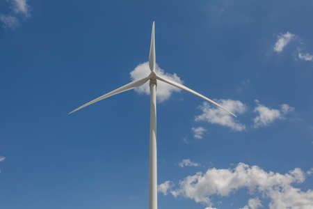 A low angle shot of a windmill under the sunlight and a blue sky at daytime - environmental concept