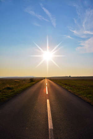 A mesmerizing view of the sunset over a field roadの写真素材