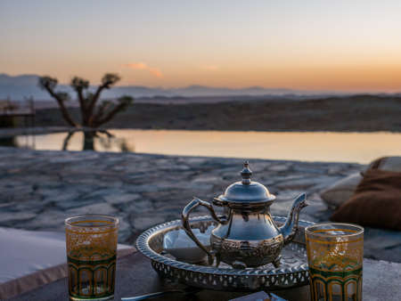 A  selective focus closeup shot of a typical Moroccan mint tea set on the table in  Agafay desert,...