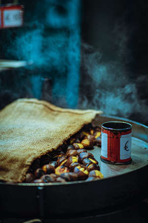 A vertical closeup of roasted nuts with a can on a pan under the lights with a blurry backgroundの写真素材