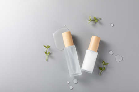 A top view of skincare bottles on a surface with green plants