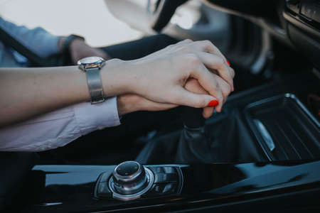 A romantic couple holding hands on a gear shift while driving a car