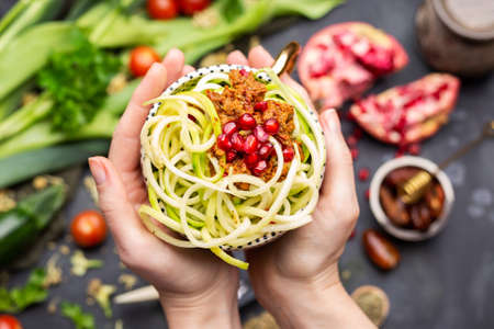 A top view of a vegan meal with spiralized zucchini, tomato sauce and pomegranates in the cupの写真素材
