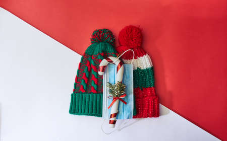 A top view of knitted Christmas hats with Christmas decorations and a medical mask - new normalの写真素材