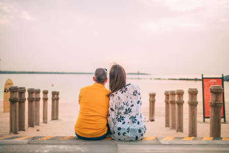 A closeup shot of a couple sitting near the beach at sunsetの写真素材