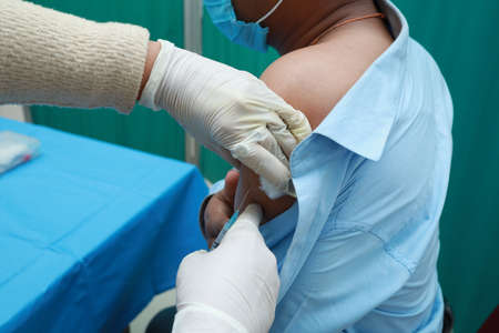 A doctor injecting vaccine in the shoulder of a patient