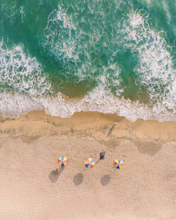 A top view shot of beach umbrellas and people lying on the sand in Varkala Beachの写真素材