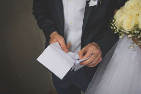A closeup shot of a groom opening an envelopeの写真素材