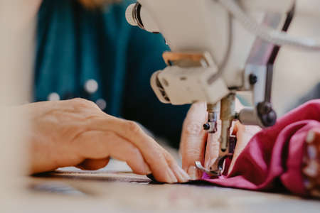 A selective focus shot of seamstress hands working on sewing machine