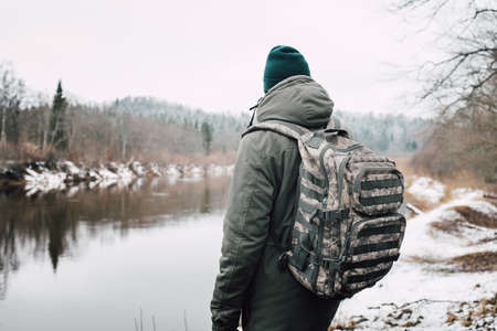 A person in front of the lake surrounded by trees during winterの写真素材