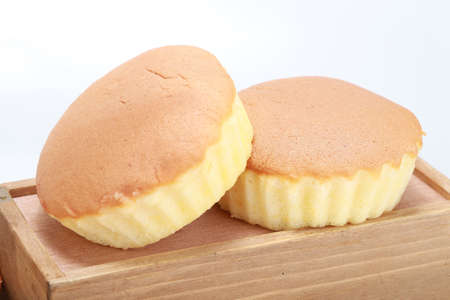 A closeup shot of two delicious freshly baked cupcakes on a wooden box with a white background
