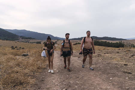 A group of hikers walking in a meadow after swimming in a waterfall pool